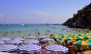 Spiaggia sabbiosa italiana con ombrelloni colorati e turisti felici in cerca di vacanze economiche.