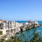 Paesaggio italiano con colline verdi e un borgo pittoresco, ideale per un weekend economico.